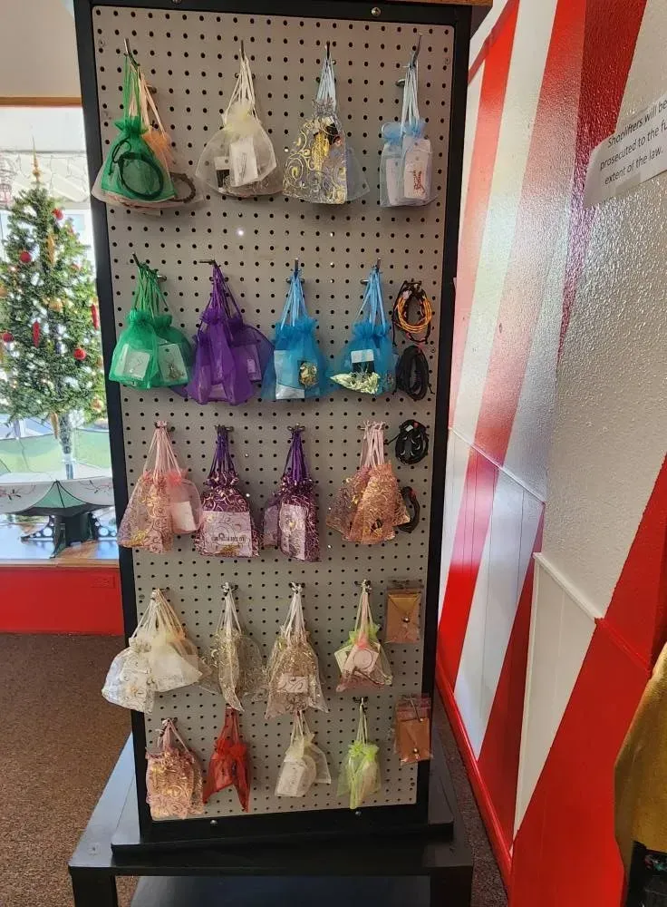Display of colorful cone-shaped gifts on a pegboard, next to a red and white striped barrier, and a Christmas tree.