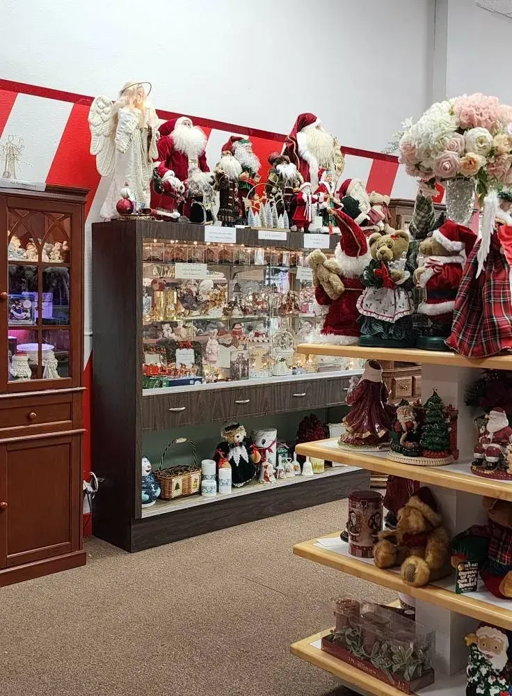 Christmas shop interior with Santa decorations, shelves of ornaments, and a wooden display case.