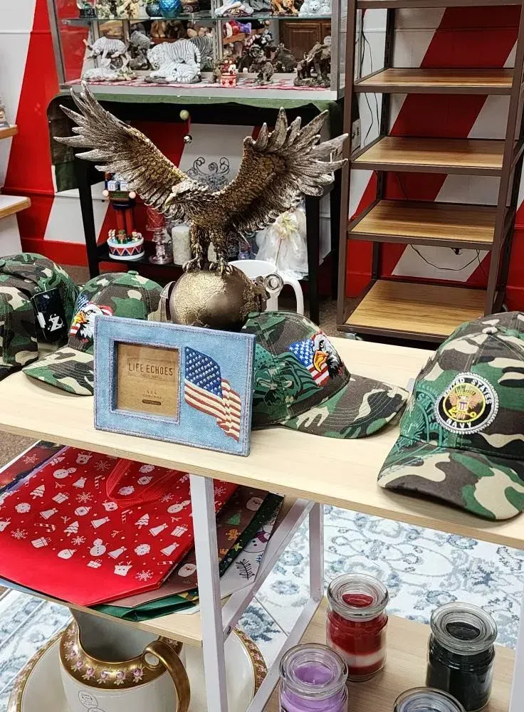 Display table with an eagle statue, camouflage hats, American flag frame, and candles.