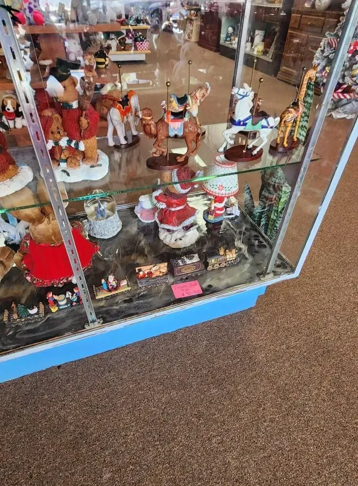 Display case with figurines, including Santa hats, bears, and other collectibles, in a store.