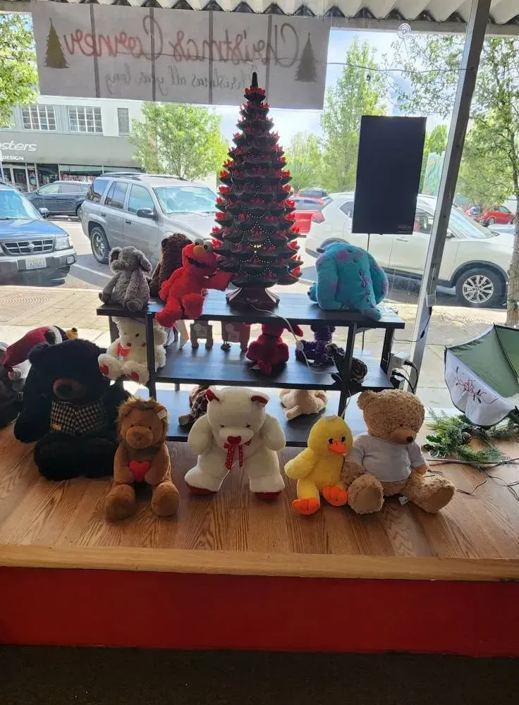 Teddy bears and a Christmas tree display in a shop window, with cars and buildings visible outside.