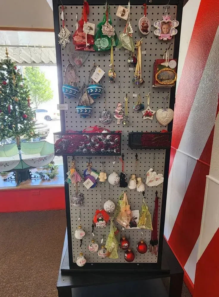 Christmas ornaments displayed on a gray pegboard in a store.