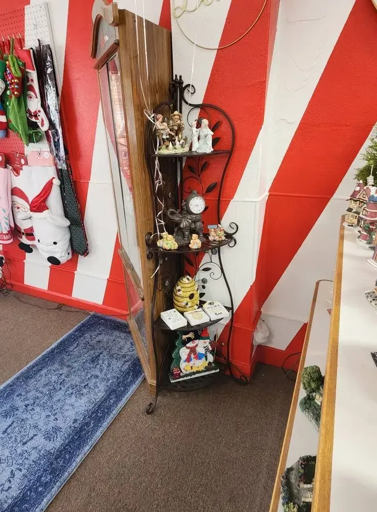 A decorative metal shelf with figurines in a shop with red and white striped walls.