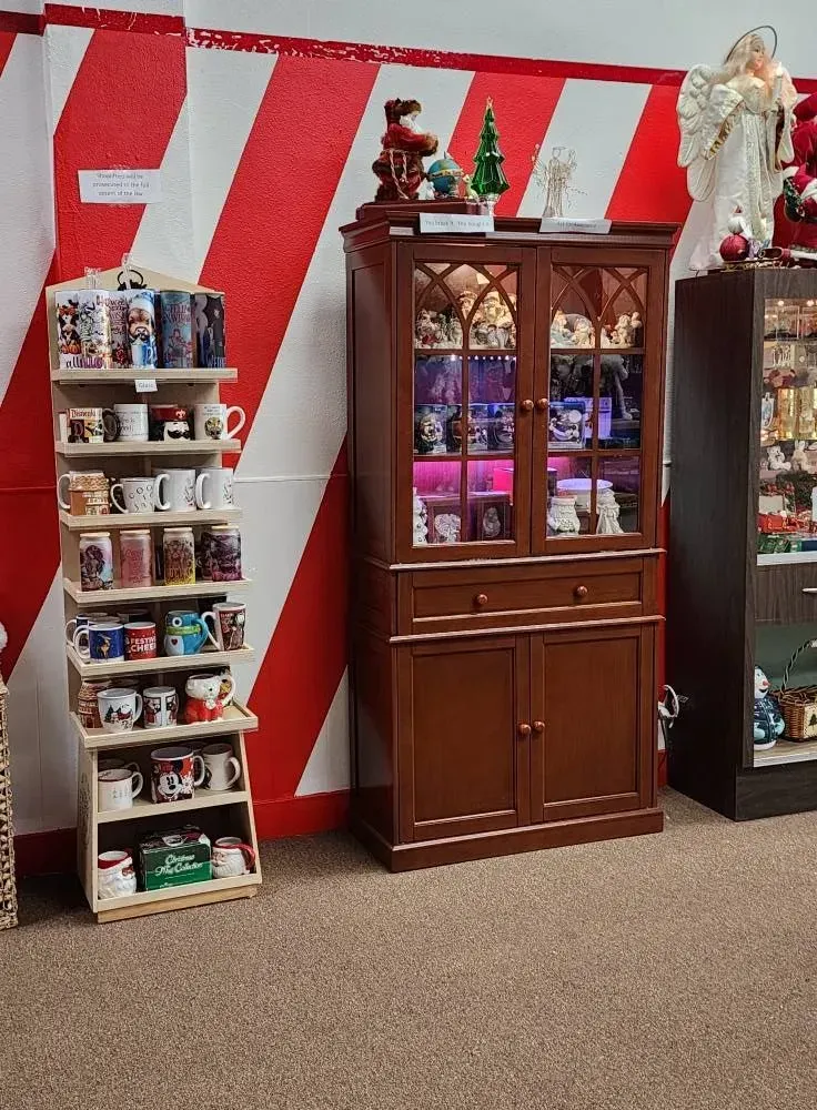 Display of mugs on shelves, a wooden cabinet, and a shelf, against red and white striped wall.