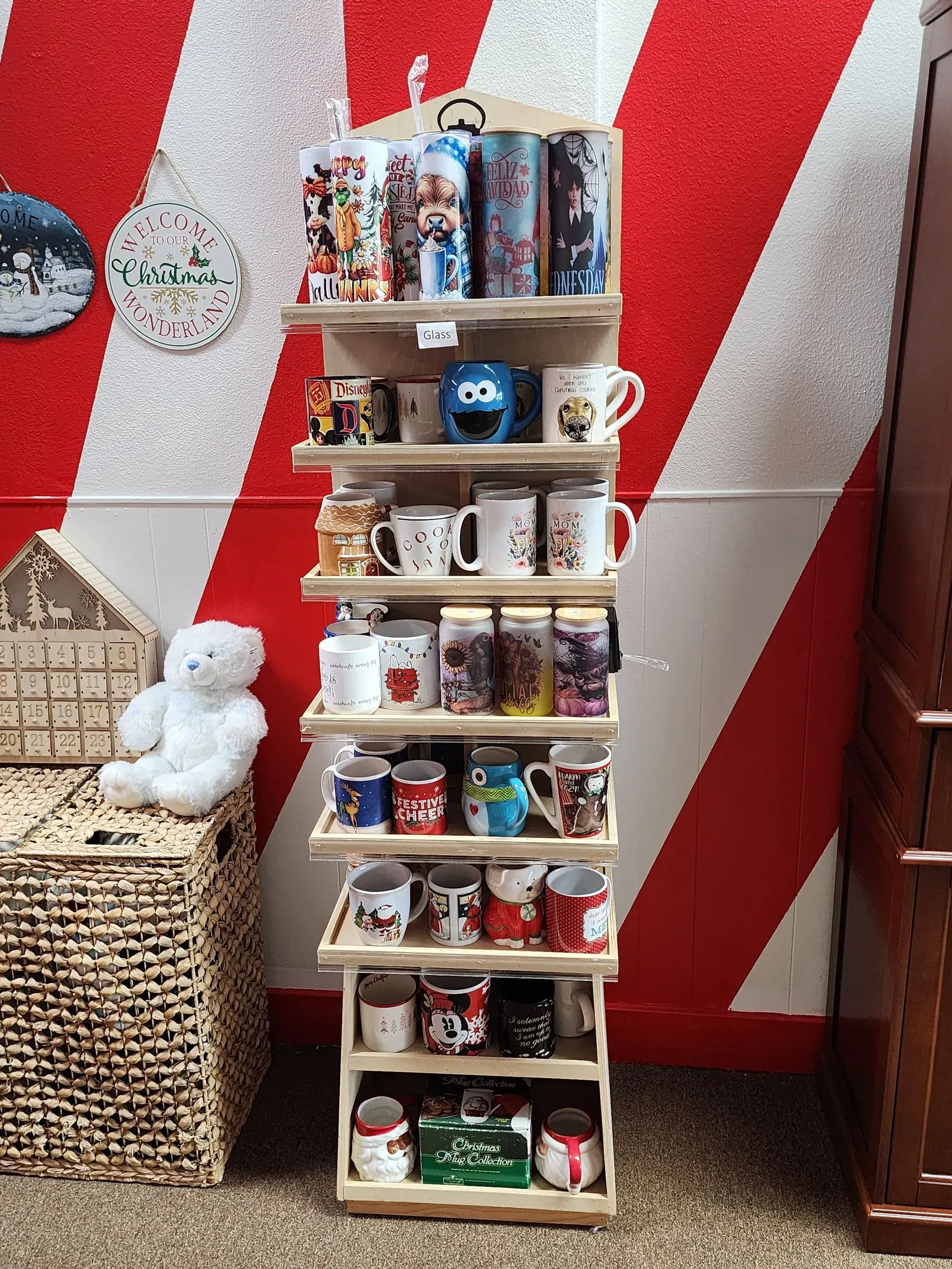 Shelf display with various mugs against a red and white striped wall.