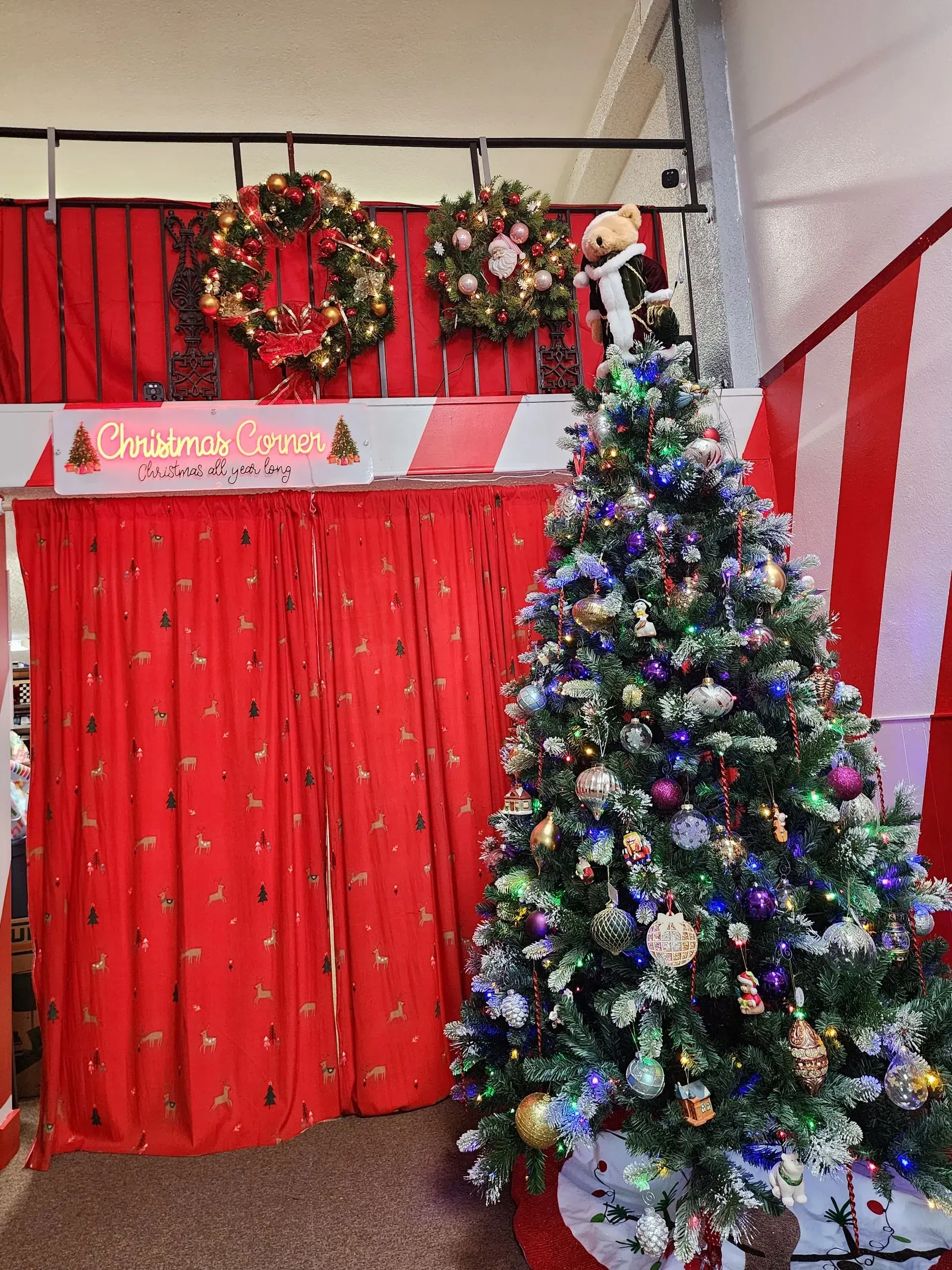 Christmas tree and red curtains with festive wreaths and decorations.