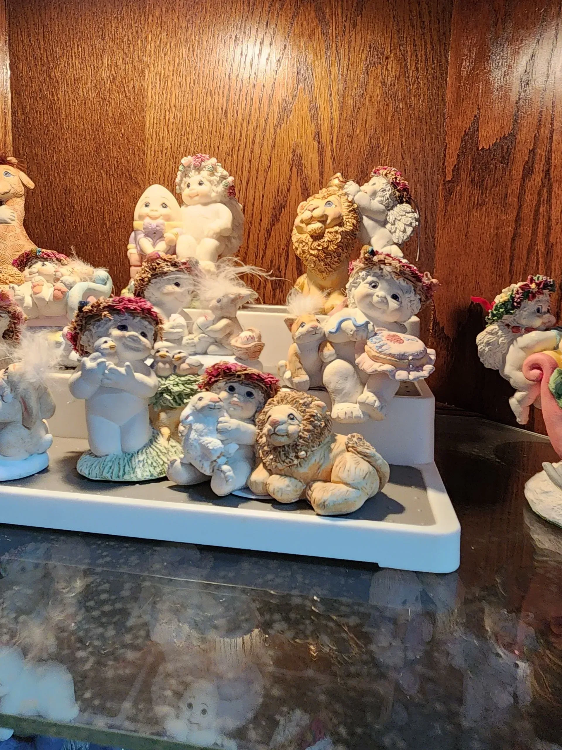 A collection of small cherub figurines with floral wreaths on a tiered display shelf.
