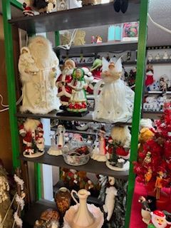 Shelving unit filled with Christmas decorations, including Santa figures, ornaments, and figurines. Green frame.