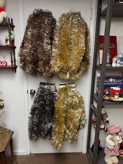 Four sets of metallic tinsel hanging on a door, brown, gold, silver, and yellow.