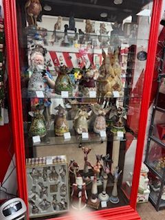 Glass display cabinet with various animal figurines, mostly bunnies, in a shop. Red trim.