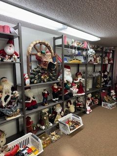 Shelves displaying numerous Christmas decorations, including Santa figures, ornaments, and a wooden wheel.