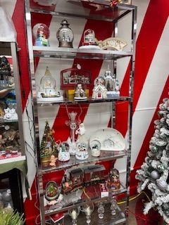 A chrome shelf displays Christmas snow globes and decorations against a red and white striped background.