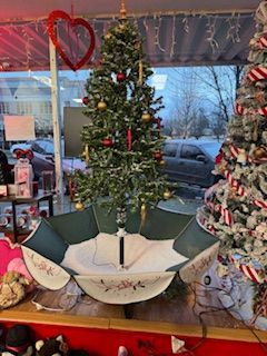 Christmas tree inside an open, decorative umbrella, displayed in a store window with a red heart decoration.