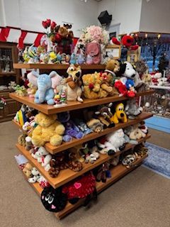 Shelves overflowing with stuffed animals in a store setting.