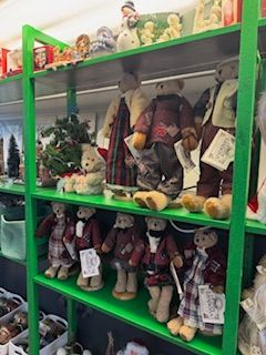 Green shelves display teddy bears of various sizes and outfits.