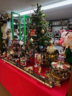 Christmas decorations displayed on a red-covered table, featuring a tree, Santa figures, and a train set.