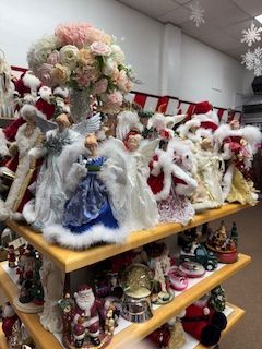 Shelves filled with Christmas decorations: Santas, angels, snow globes, and floral arrangement.