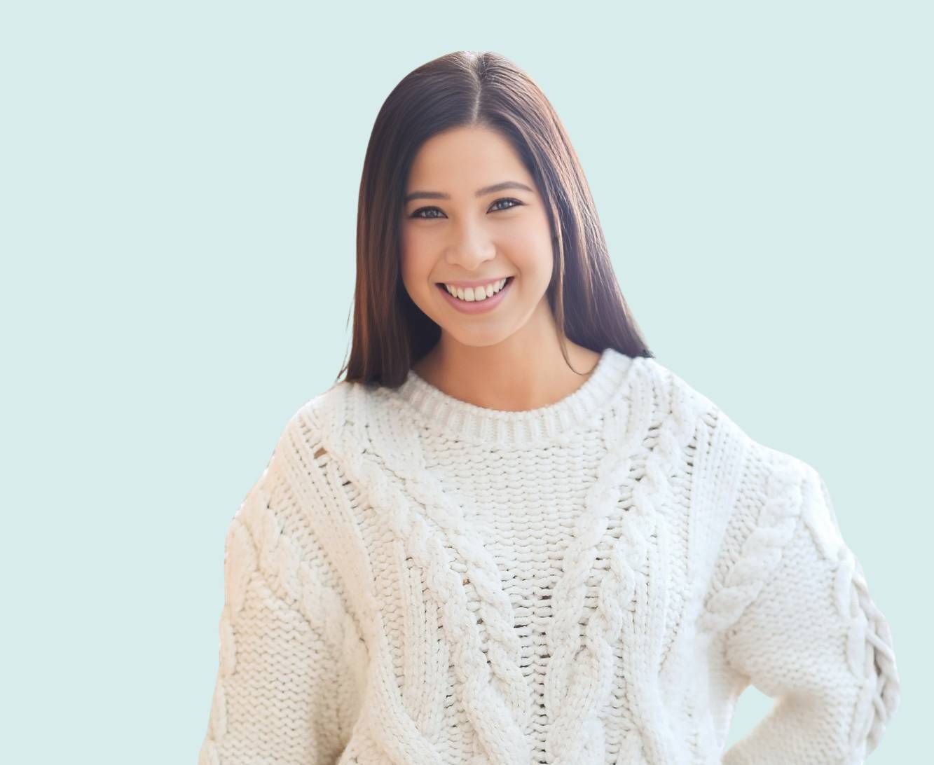 A woman is wearing a white sweater and smiling.