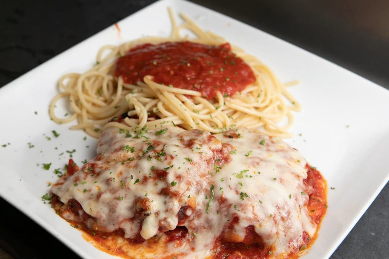 A margherita pizza with tomatoes, mozzarella cheese and basil on a metal pan.