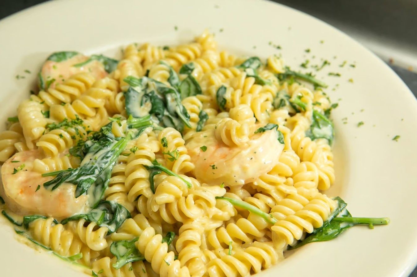 A margherita pizza with tomatoes, mozzarella cheese and basil on a metal pan.