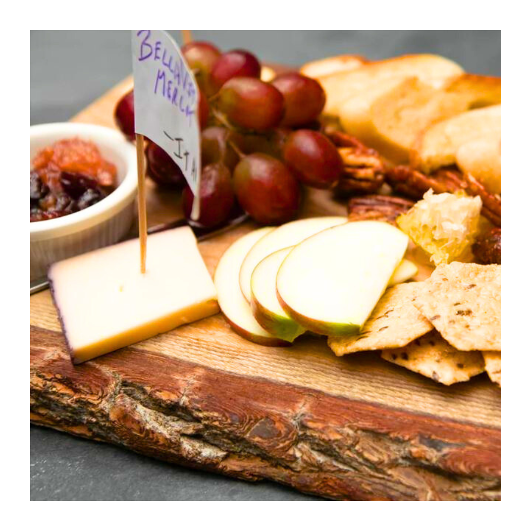 Cheese board: cheese, grapes, apple slices, crackers, nuts, and jam.