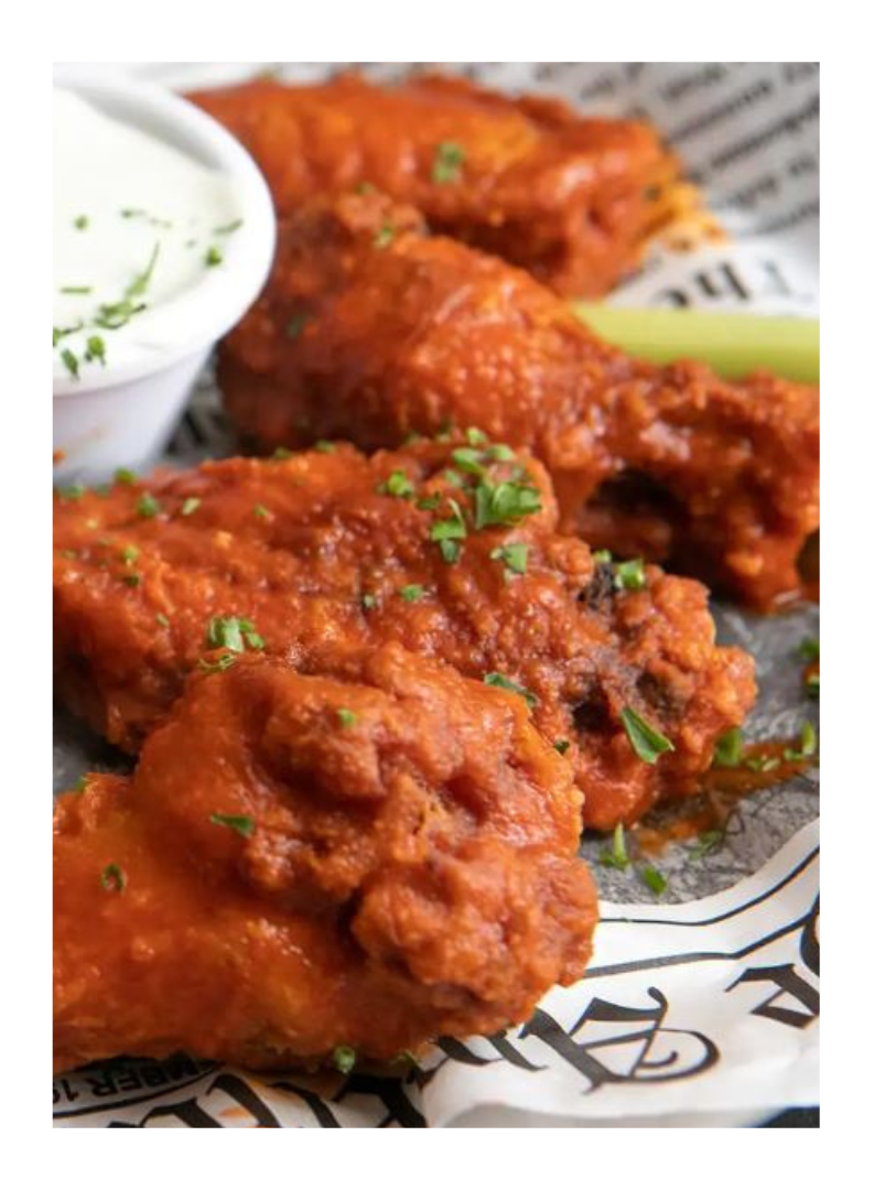 Close-up of crispy, red buffalo wings with blue cheese dip and a celery stick.