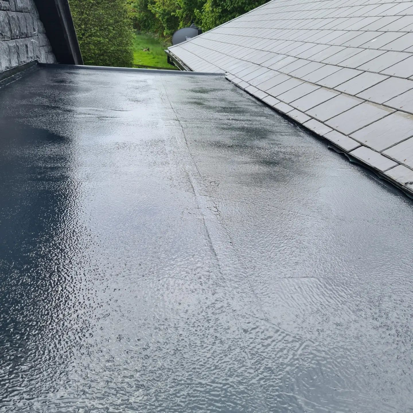 Two roofers torching and rolling roofing material on a flat roof.