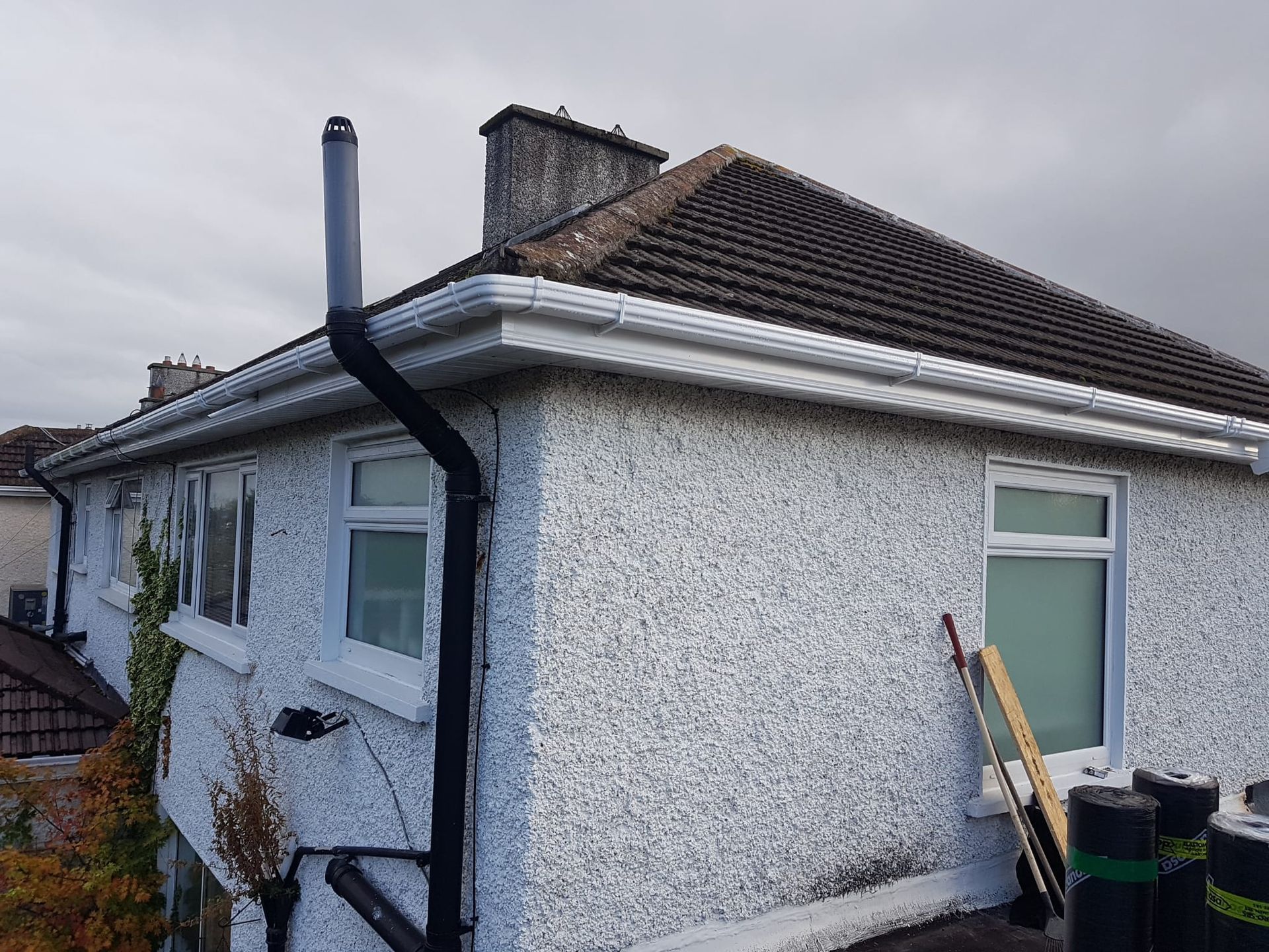 White gutters and downspout attached to a brick building.