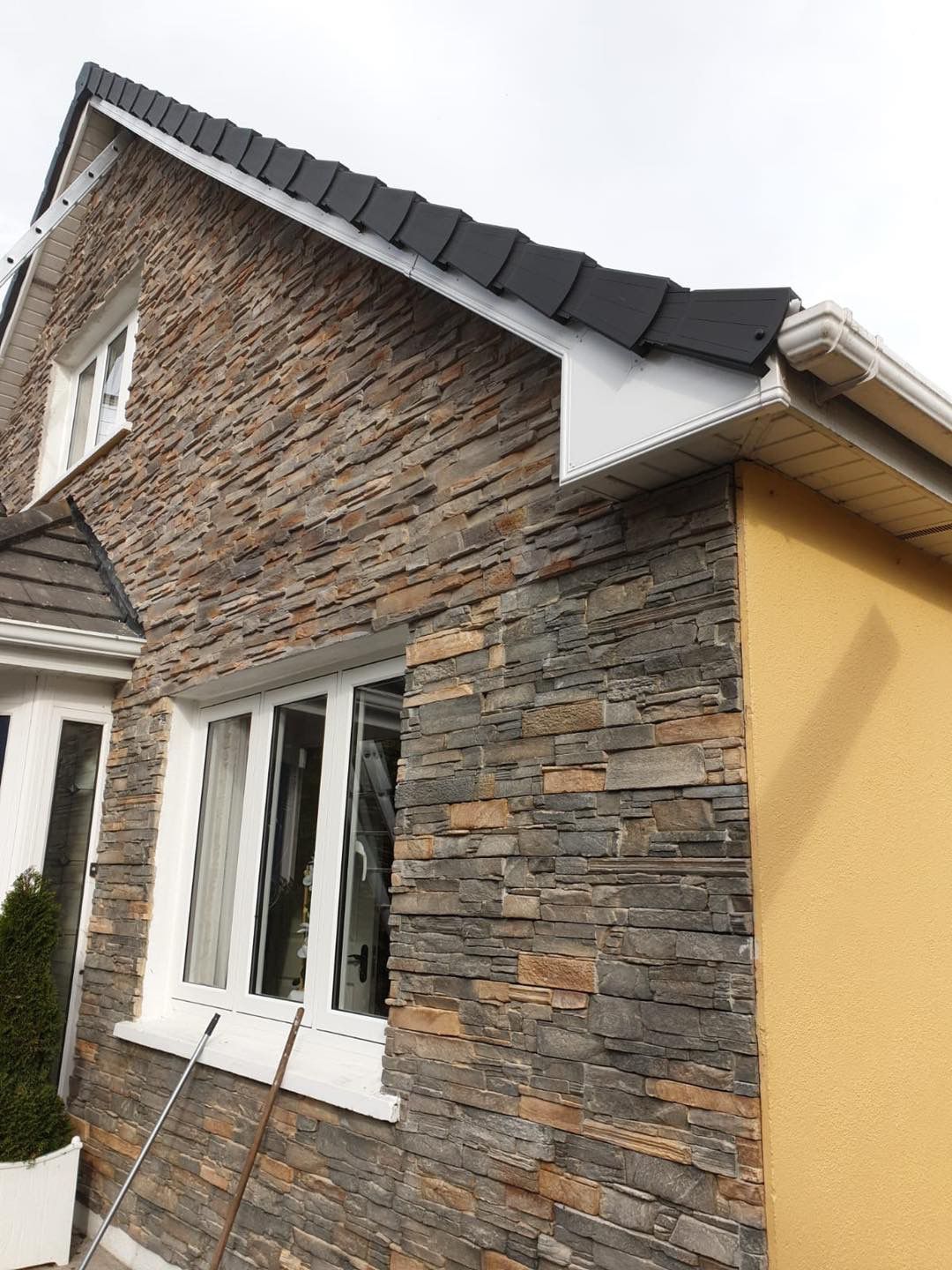 A brick building with a dark tiled roof and black trim against a clear blue sky.