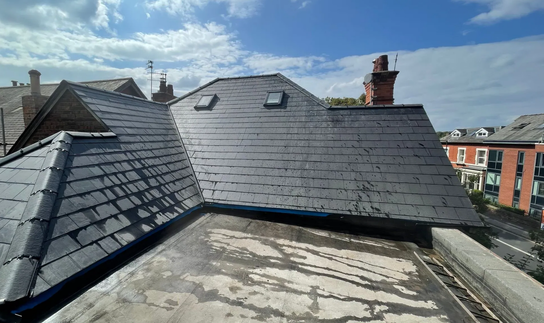 Aerial view of a house with scaffolding and roof tiles partially removed. Trees and yard surround the building.