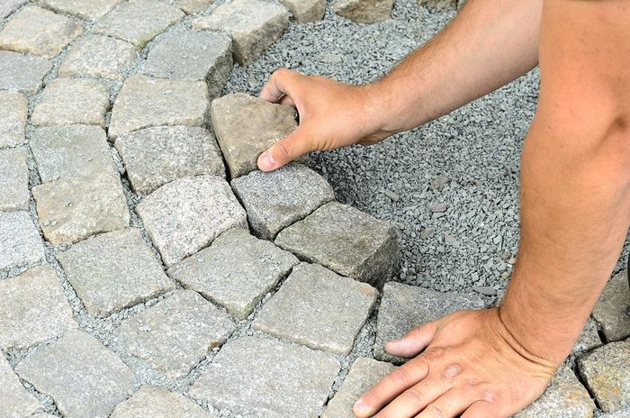 someone putting stone for paving