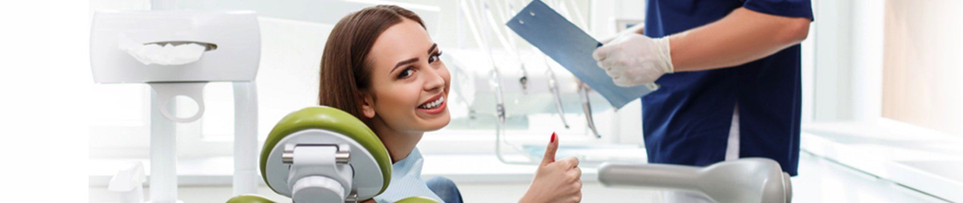 A woman is sitting in a dental chair talking to a dentist.