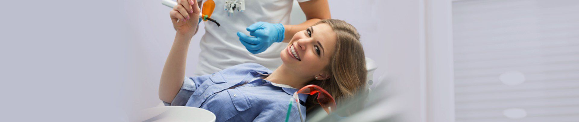 A young girl is sitting in a dental chair while a dentist examines her teeth.