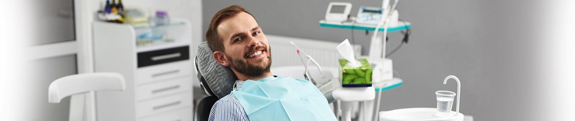 A man is smiling while sitting in a dental chair.