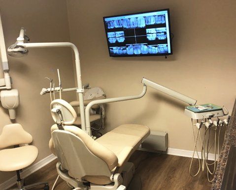 A dental office with a dental chair and a tv on the wall