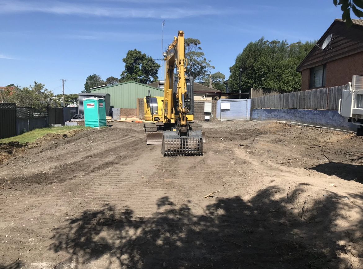 A yellow excavator is driving down a dirt road.