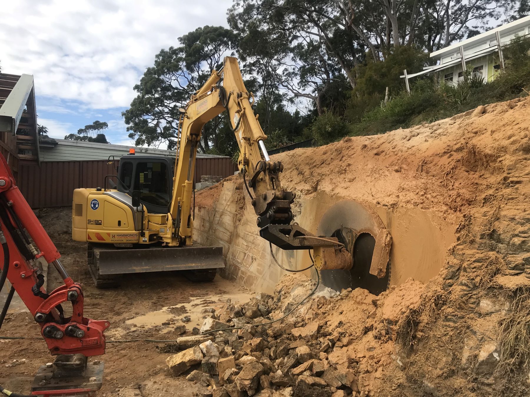 A yellow excavator is digging a hole in the ground.