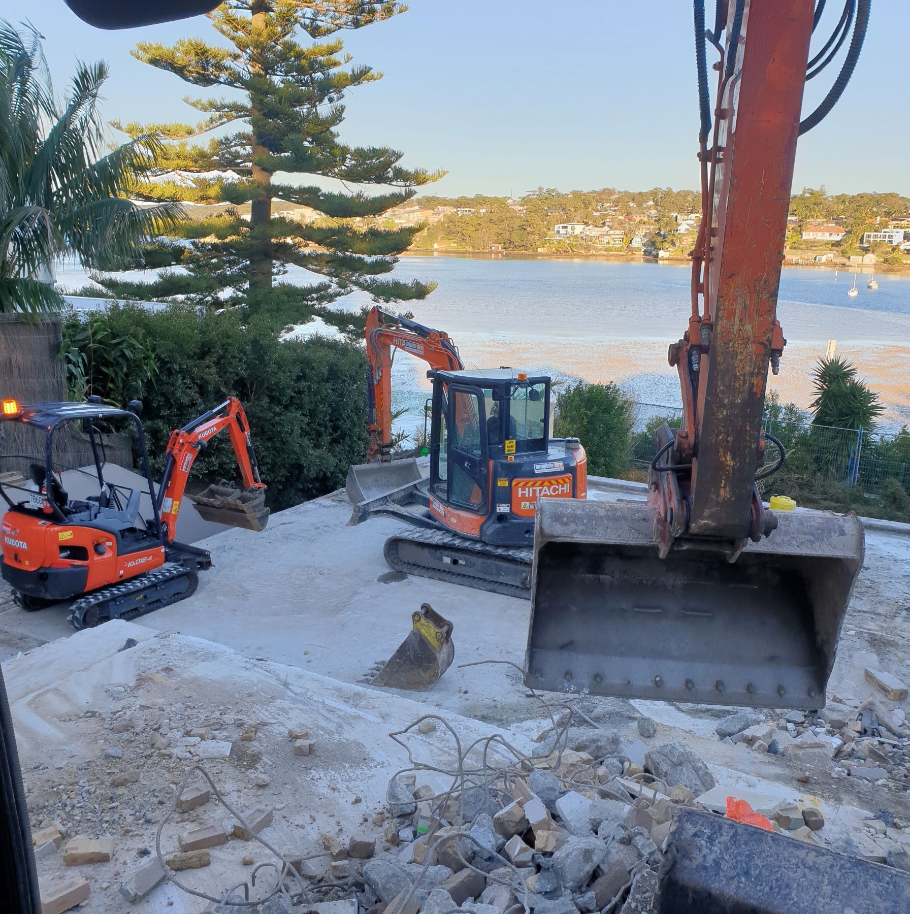 A couple of excavators are working on a construction site near a body of water