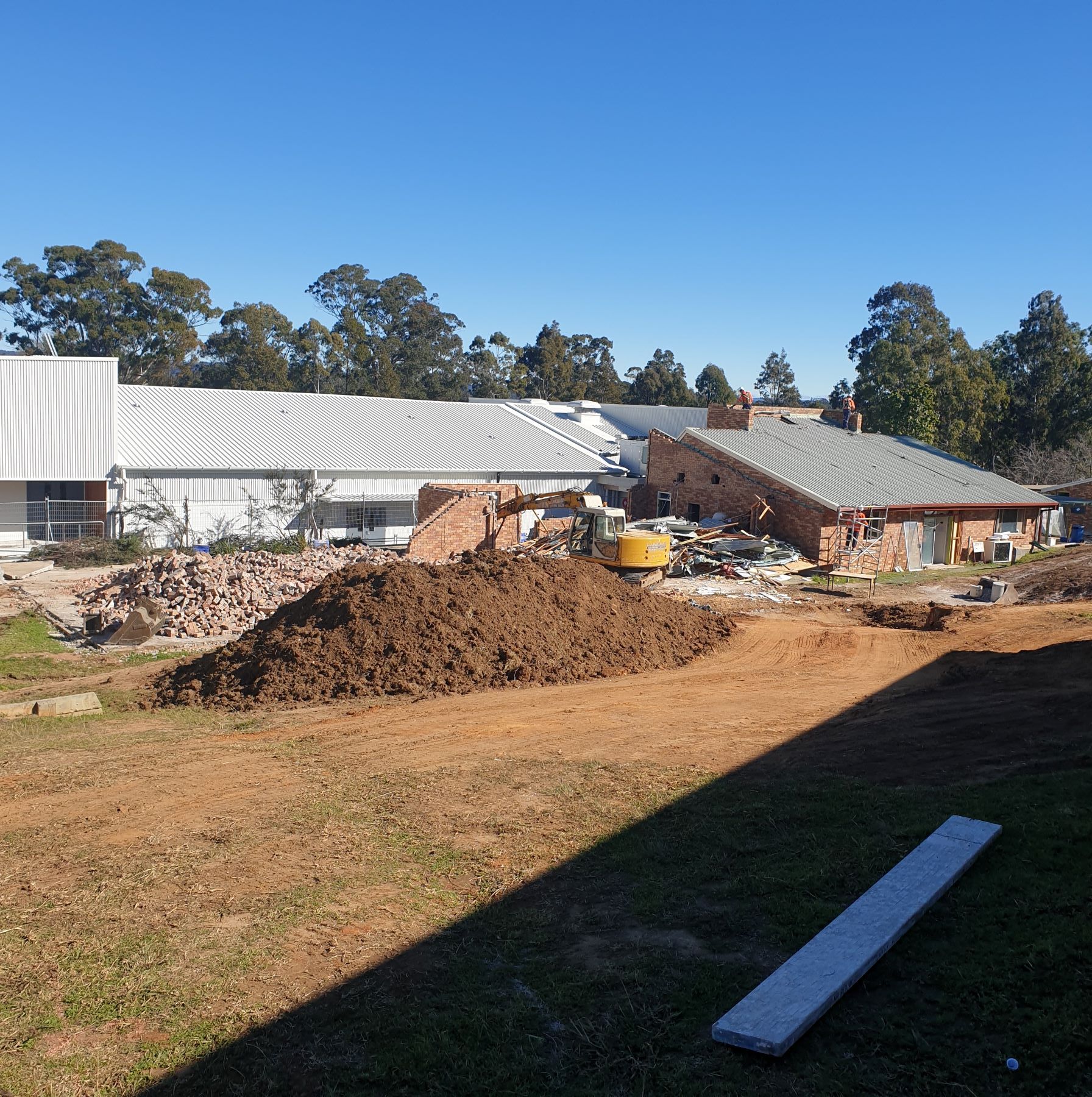 A large pile of dirt is in front of a building under construction