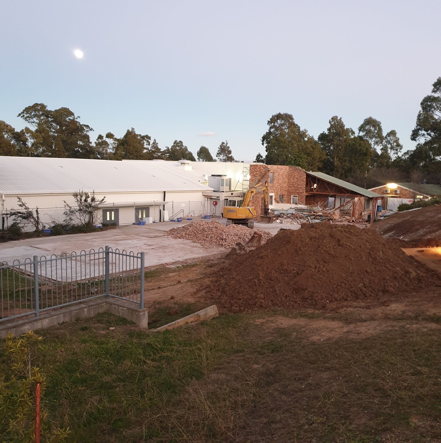 A large pile of dirt is in front of a building under construction
