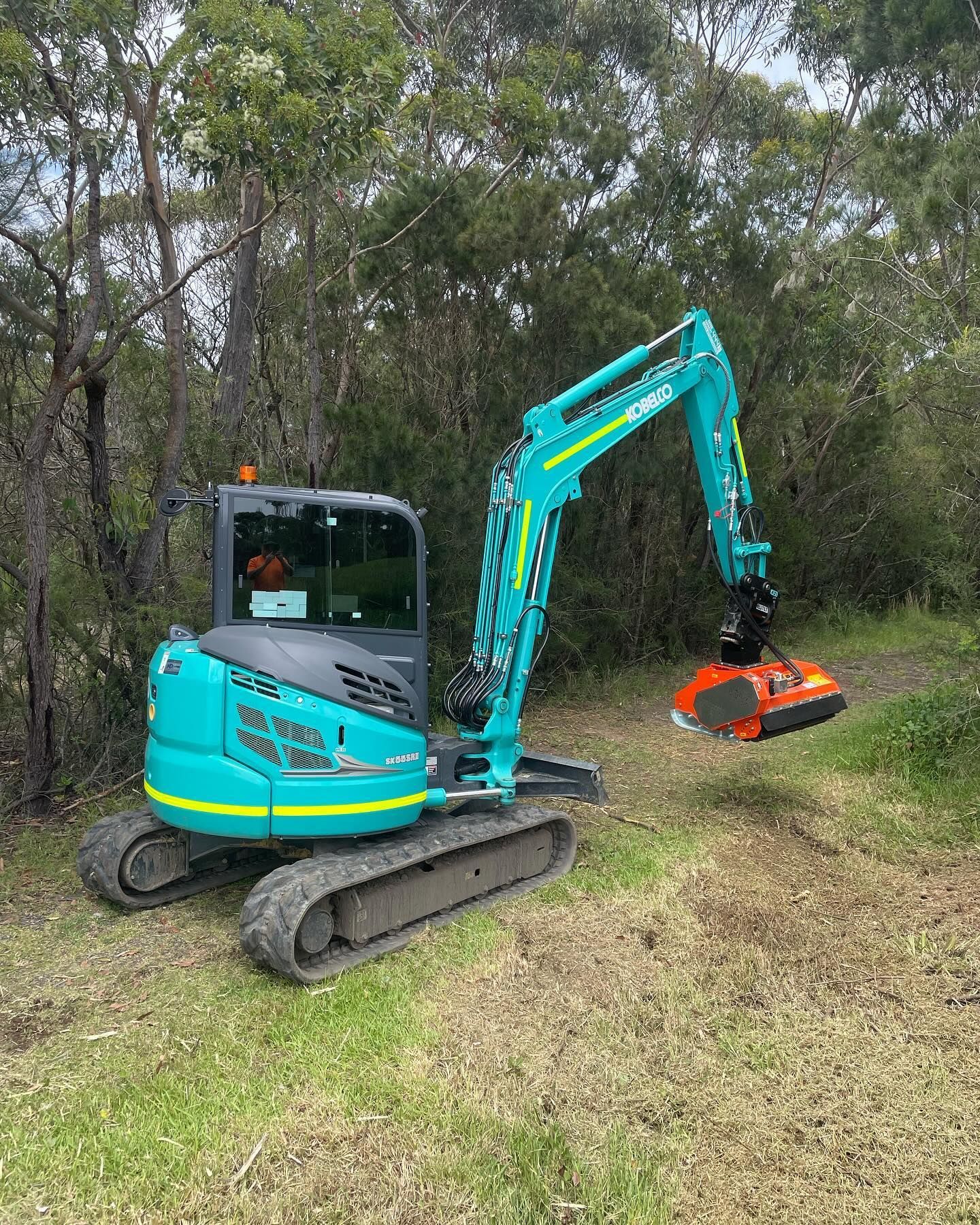 A small blue excavator is sitting on top of a lush green field.