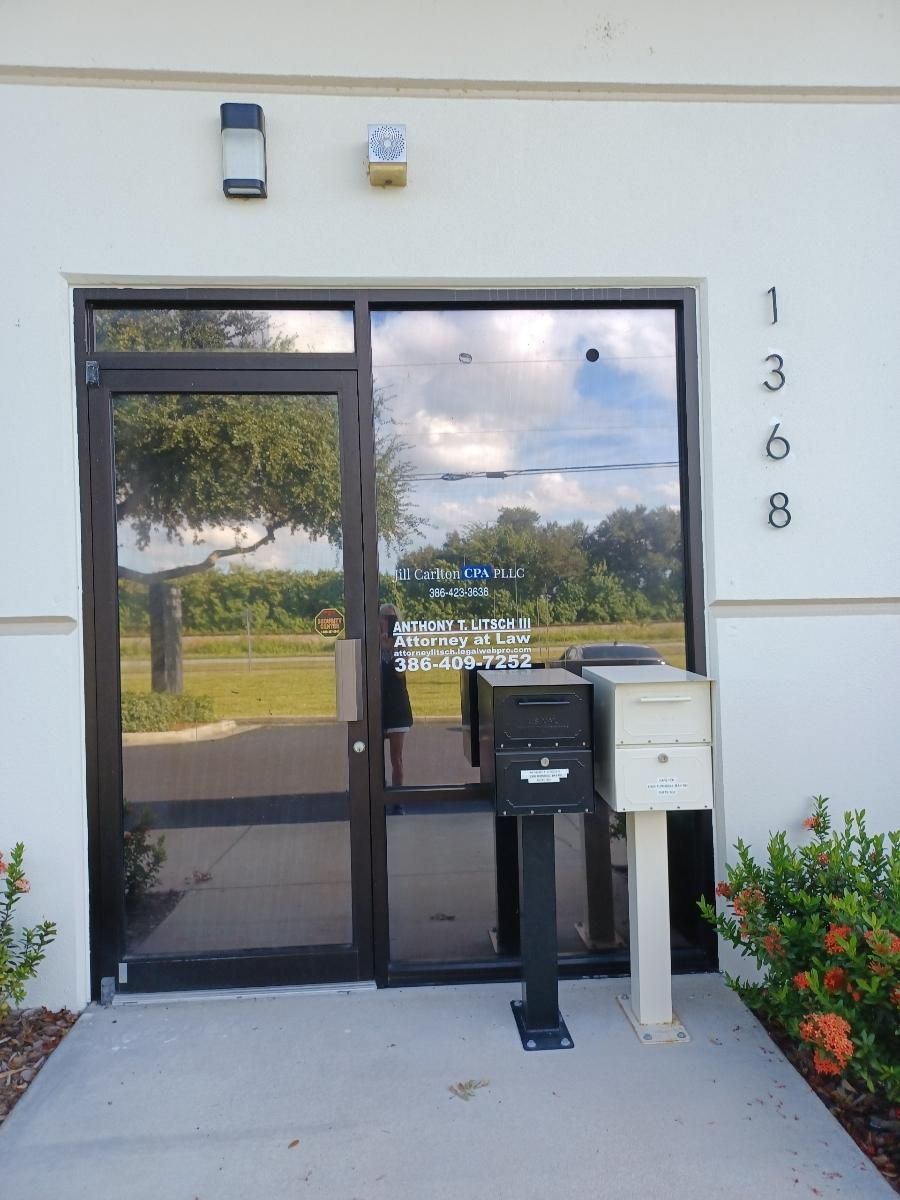 Exterior view of a building with a glass door and mailbox. Address is visible, with a sign for Big Sky VCP.