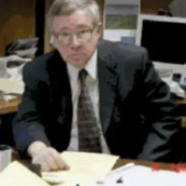 A man in a suit and tie is sitting at a desk