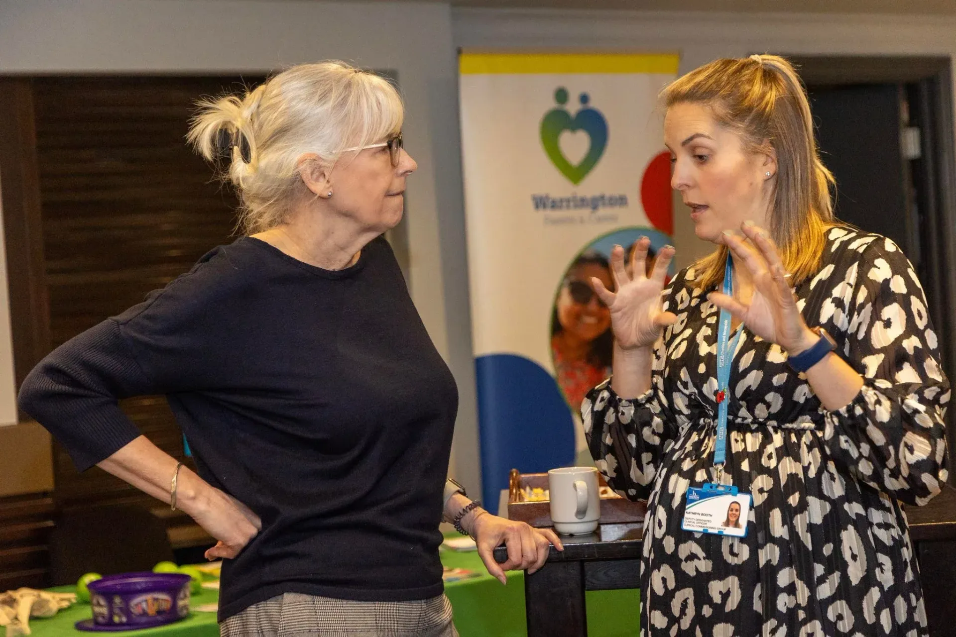 Two women are talking to each other in a room.
