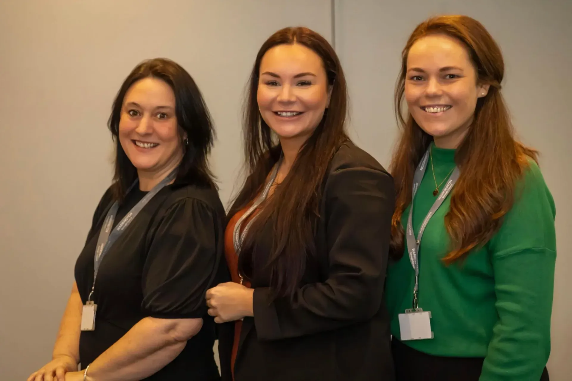Three women are standing next to each other and smiling for the camera.