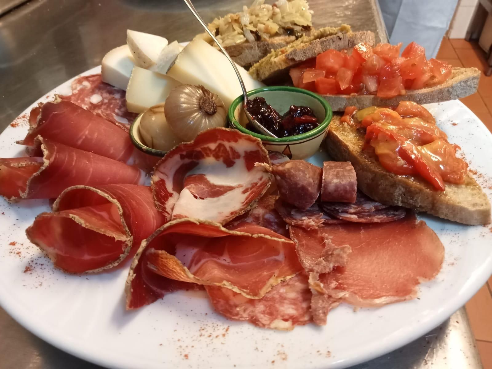 Un piatto bianco con sopra una varietà di carni e verdure