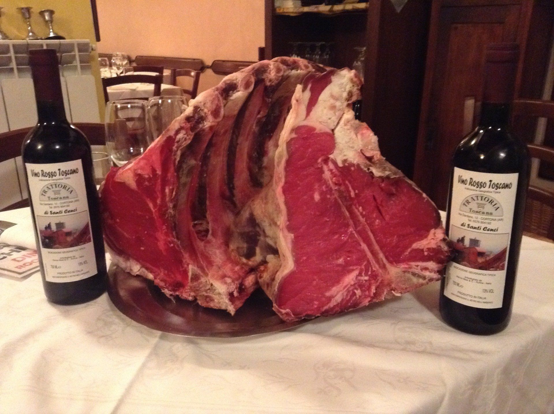 Due bottiglie di vino e un grosso pezzo di carne su un tavolo