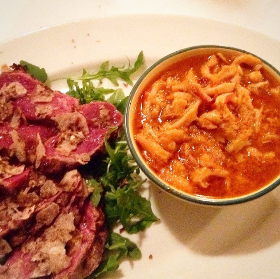 Un piatto bianco con sopra carne e una ciotola di salsa