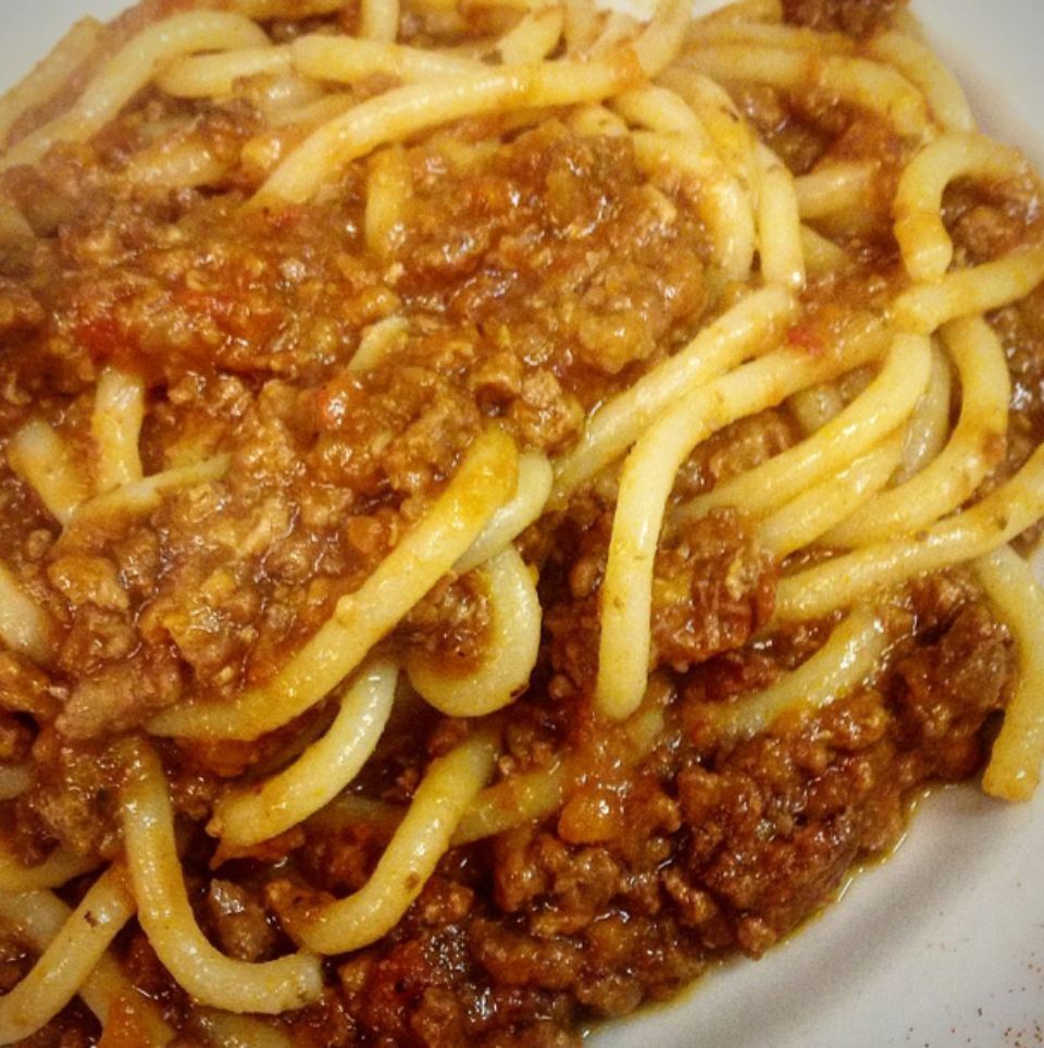 Un piatto bianco condito con spaghetti e sugo di carne
