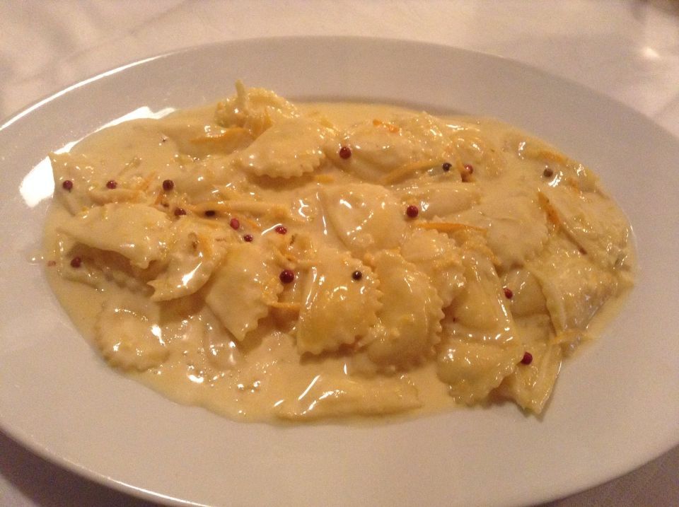 Un piatto bianco condito con ravioli in salsa cremosa